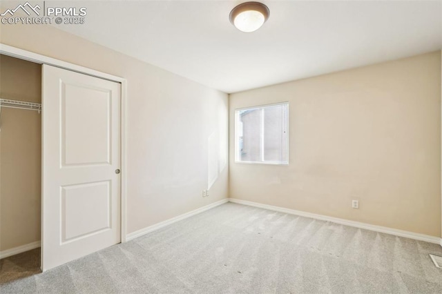 unfurnished bedroom with light colored carpet and a closet