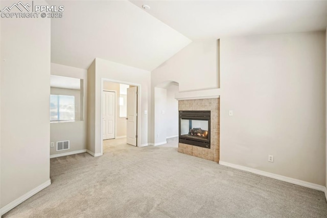 unfurnished living room featuring light carpet, lofted ceiling, and a tiled fireplace