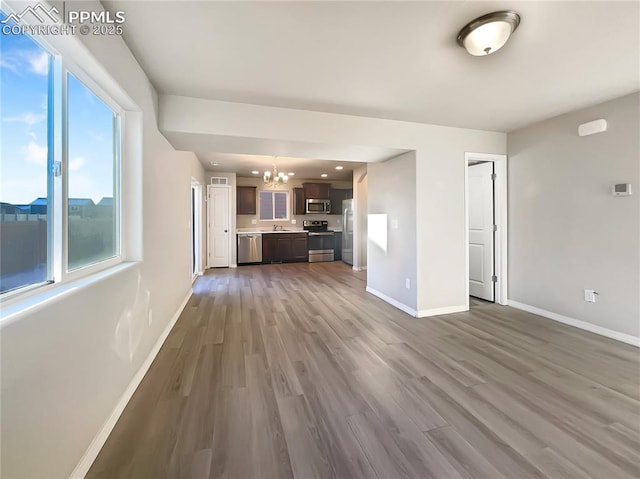 unfurnished living room featuring wood-type flooring and a chandelier