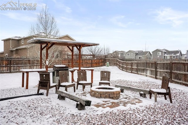 snow covered patio featuring area for grilling and a fire pit