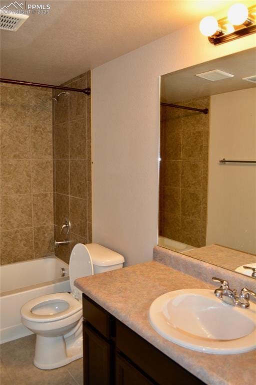 full bathroom with tile patterned flooring, vanity, tiled shower / bath combo, and toilet