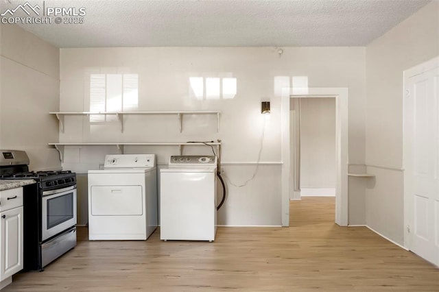 laundry room featuring separate washer and dryer, a textured ceiling, and light hardwood / wood-style flooring