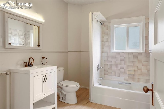 full bathroom featuring hardwood / wood-style flooring, tiled shower / bath combo, vanity, and toilet