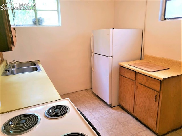 kitchen featuring white refrigerator, electric range, and sink