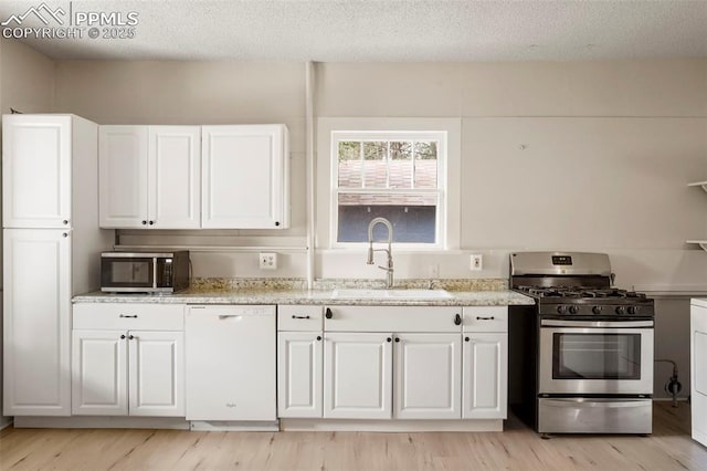 kitchen featuring white cabinets, sink, stainless steel appliances, and a textured ceiling