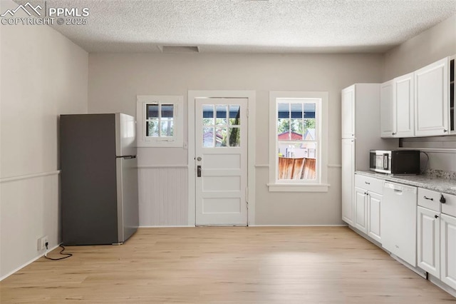 kitchen with a textured ceiling, stainless steel appliances, light hardwood / wood-style flooring, and white cabinets