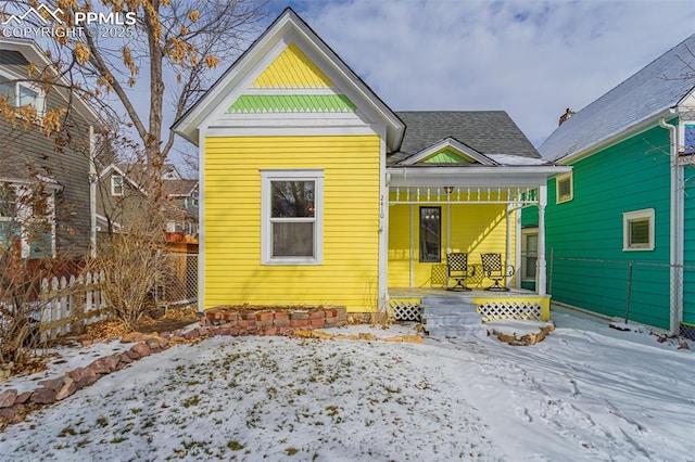 snow covered rear of property with covered porch