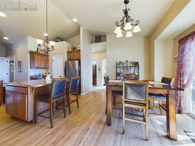 dining area featuring vaulted ceiling, light hardwood / wood-style flooring, and an inviting chandelier