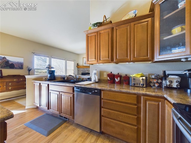 kitchen with dark stone counters, dishwasher, sink, and light hardwood / wood-style flooring