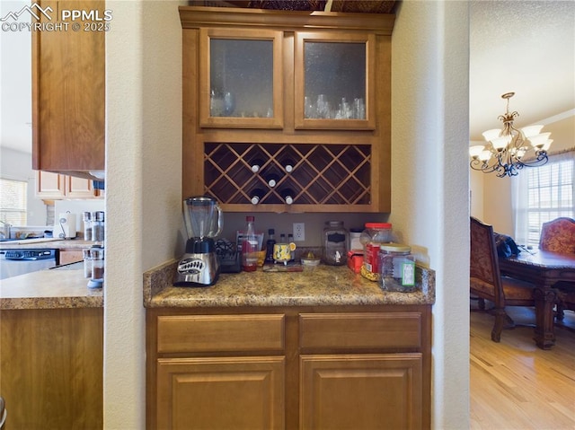 bar featuring light hardwood / wood-style floors, dishwasher, and a notable chandelier