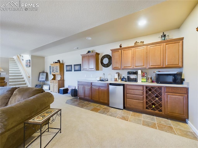 kitchen with sink, light colored carpet, dishwasher, and a textured ceiling