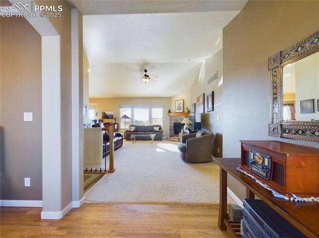 carpeted living room with ceiling fan, a fireplace, and lofted ceiling