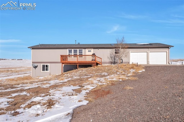 view of front of property featuring dirt driveway, a wooden deck, and a garage