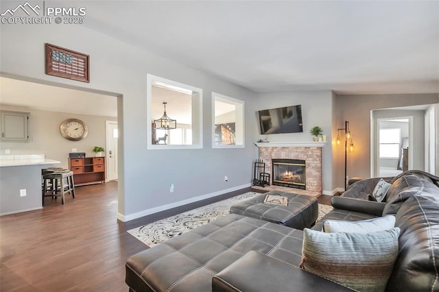 living room with dark wood-style floors, baseboards, and a glass covered fireplace