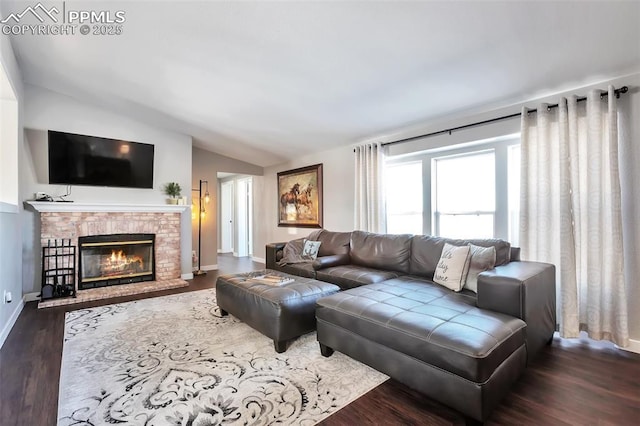 living area with a fireplace, baseboards, vaulted ceiling, and dark wood-style flooring