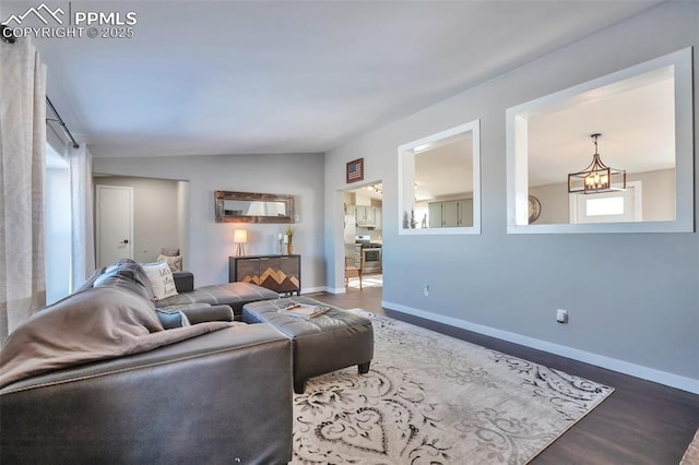 living room featuring an inviting chandelier, baseboards, and wood finished floors