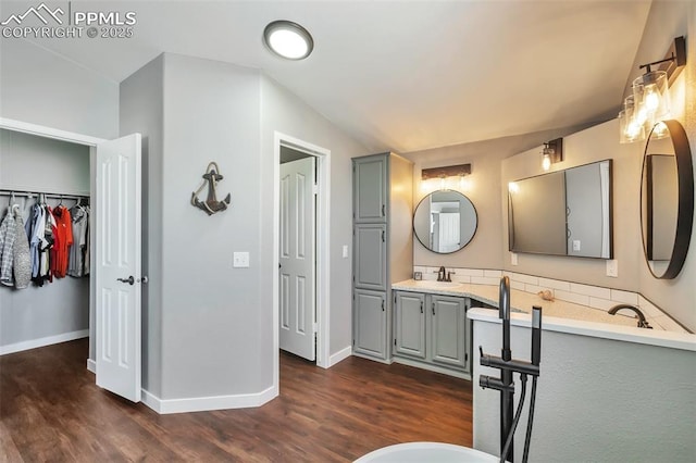 bathroom featuring lofted ceiling, baseboards, wood finished floors, and vanity