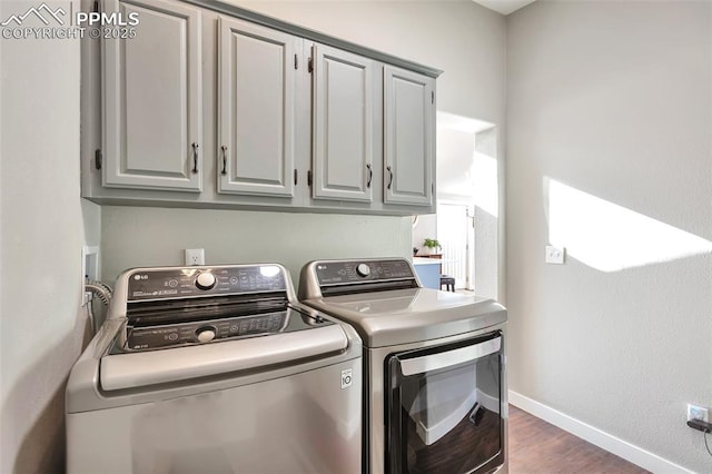 washroom with dark hardwood / wood-style floors, washing machine and clothes dryer, and cabinets