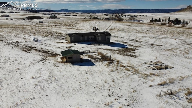 snowy aerial view featuring a rural view and a mountain view