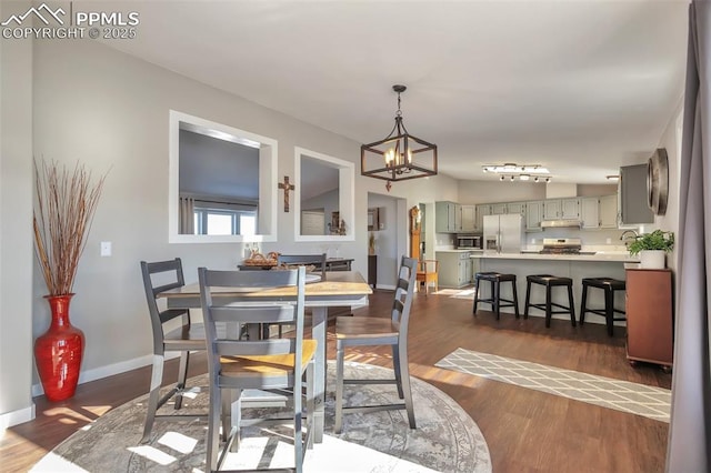 dining space with dark wood-style floors, baseboards, and an inviting chandelier