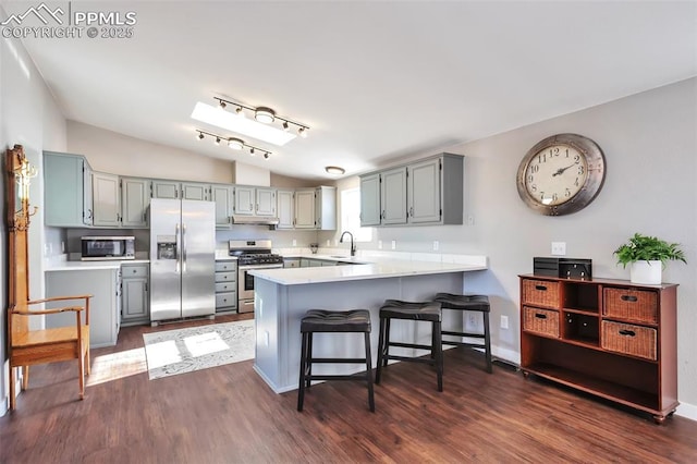 kitchen with lofted ceiling, dark hardwood / wood-style floors, a breakfast bar, kitchen peninsula, and stainless steel appliances