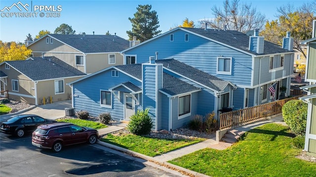 view of front facade featuring a chimney, a front lawn, central AC unit, and uncovered parking