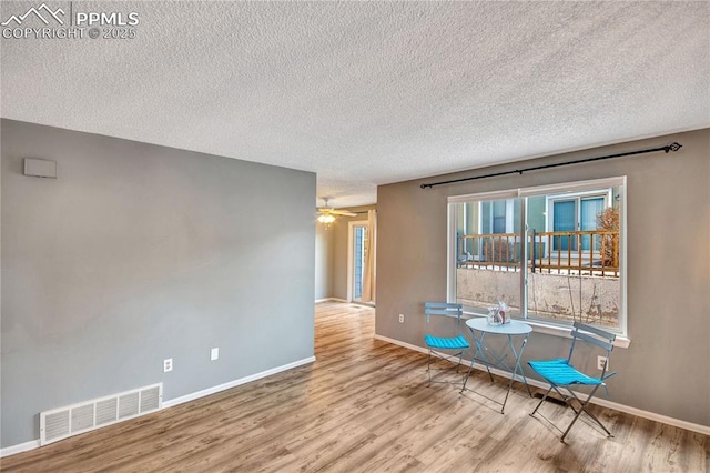 unfurnished room featuring light wood-type flooring, a textured ceiling, and ceiling fan