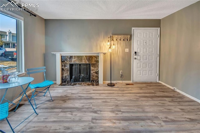 unfurnished living room featuring wood-type flooring, a textured ceiling, and a stone fireplace