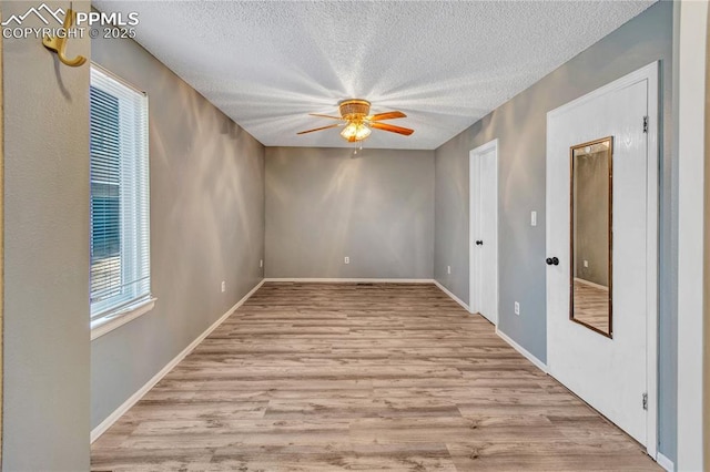 empty room featuring ceiling fan, light hardwood / wood-style floors, and a textured ceiling