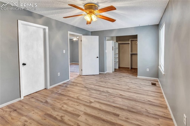 unfurnished bedroom featuring ceiling fan, multiple windows, and light hardwood / wood-style flooring