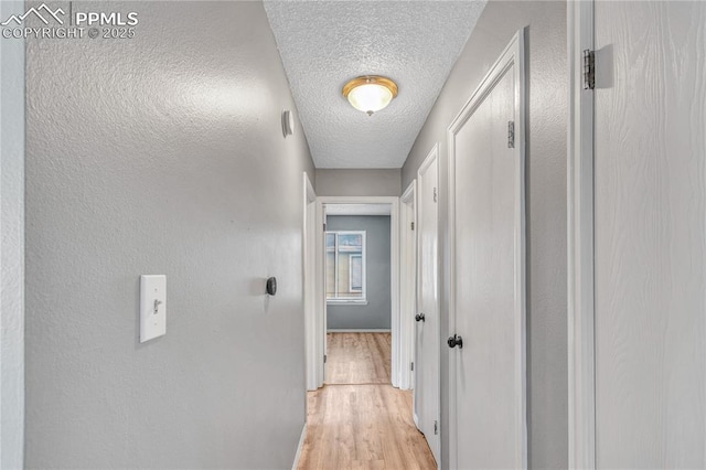 hallway featuring light hardwood / wood-style floors and a textured ceiling