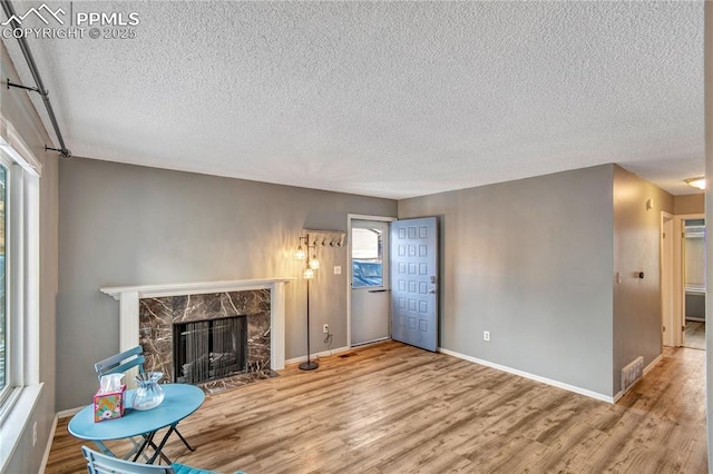 unfurnished living room featuring a textured ceiling, a fireplace, and wood-type flooring