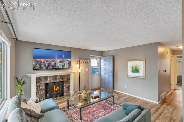 living room with hardwood / wood-style flooring, a high end fireplace, and a textured ceiling