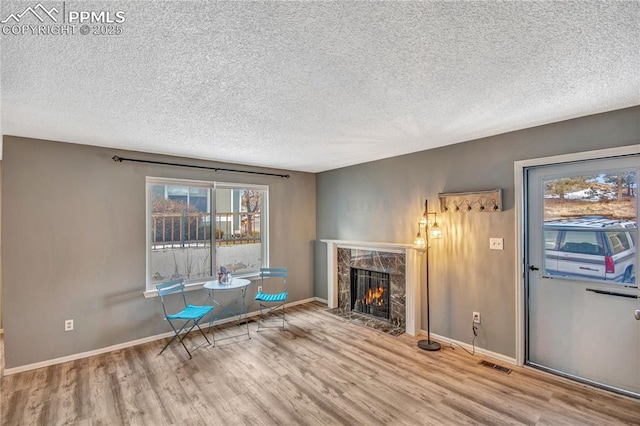 unfurnished room featuring light hardwood / wood-style flooring, a textured ceiling, and a fireplace