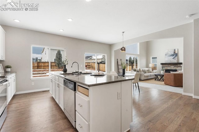 kitchen featuring sink, decorative light fixtures, white cabinetry, a center island with sink, and stainless steel appliances