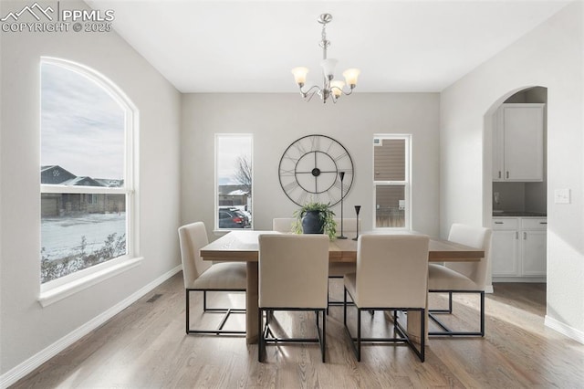 dining area with light wood-type flooring and an inviting chandelier