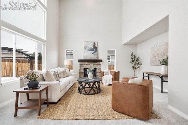 living room with a towering ceiling, a fireplace, and light carpet