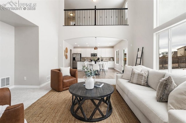 living room featuring a healthy amount of sunlight, carpet flooring, and a high ceiling