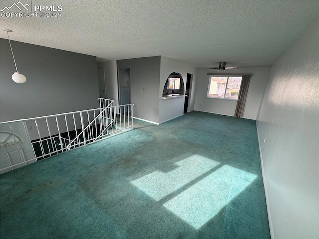 unfurnished room with ceiling fan, a textured ceiling, and carpet flooring