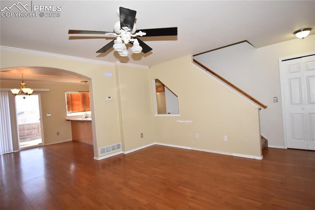 unfurnished living room featuring crown molding, dark wood-type flooring, and ceiling fan with notable chandelier