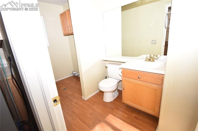 bathroom featuring wood-type flooring, toilet, and vanity