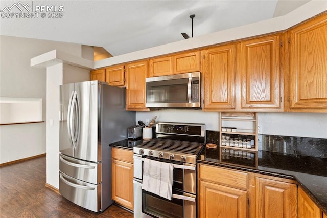 kitchen with vaulted ceiling, stainless steel appliances, dark stone countertops, and dark hardwood / wood-style flooring