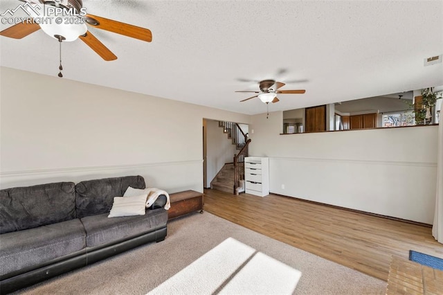 living room with light hardwood / wood-style floors, a textured ceiling, and ceiling fan