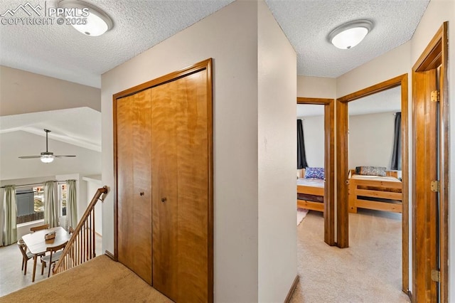 corridor featuring a textured ceiling and light carpet