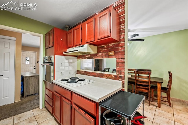 kitchen with tasteful backsplash, white electric cooktop, stainless steel oven, ceiling fan, and light tile patterned floors