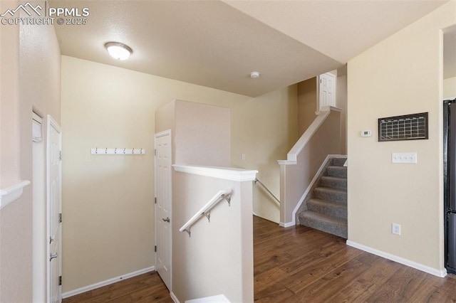 corridor featuring baseboards, wood finished floors, and an upstairs landing