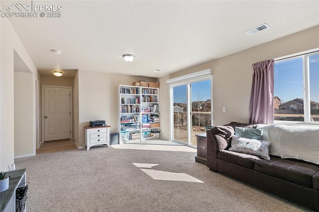 living area featuring baseboards, a textured ceiling, visible vents, and carpet flooring