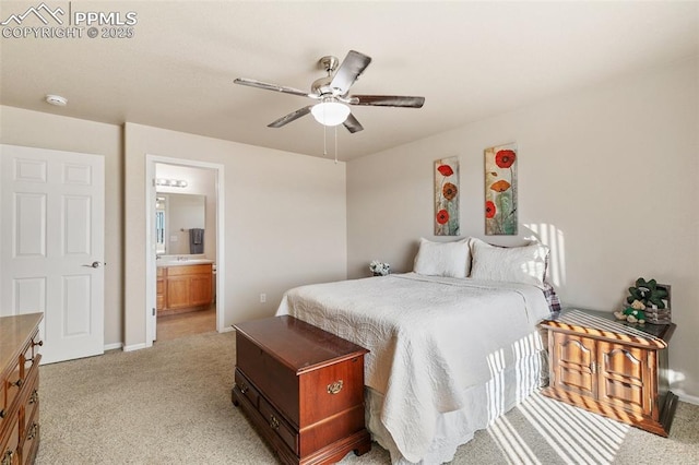 bedroom featuring a ceiling fan, light colored carpet, baseboards, and ensuite bathroom