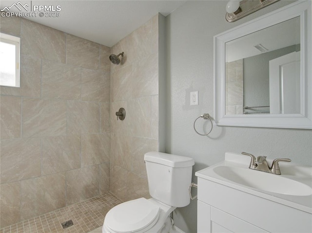 bathroom with vanity, toilet, and a tile shower