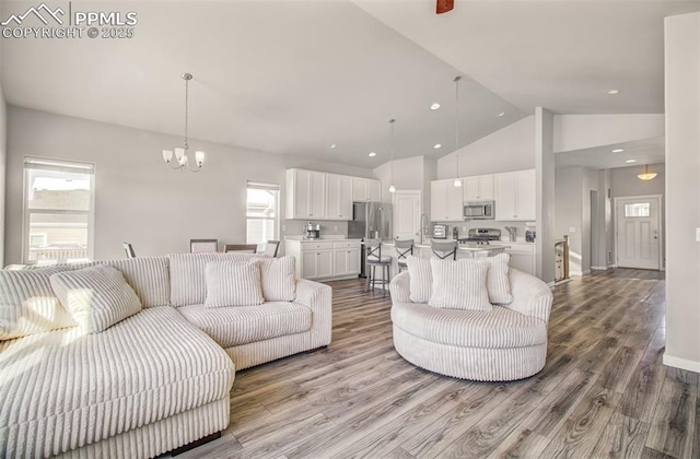 living room featuring a notable chandelier, hardwood / wood-style flooring, and high vaulted ceiling